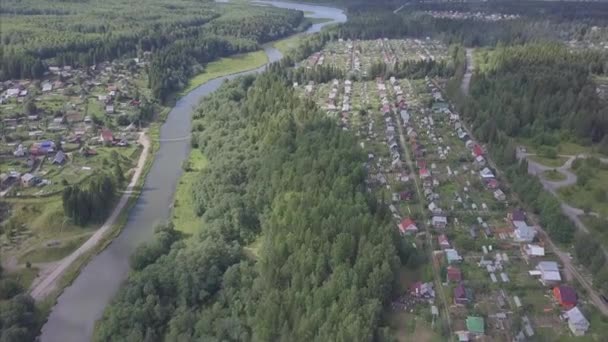 Вид з повітря на маленьке містечко поблизу лісу. Кліп. Вид на місто в лісистій місцевості з річкою — стокове відео