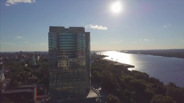 Flygfoto över floden och en modern byggnad. Klipp. Vackra stadsbilden på solnedgången — Stockvideo