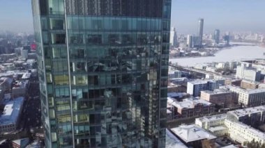 Modern gökdelenin pencereleri kapatın. Bulutlar refelected modern ofis binası içinde. Yakınlaştırma ve panning. Hava. Pürüzsüz kamera hareketi ofis windows güneşli mavi gökyüzü yansıtan binası önünde