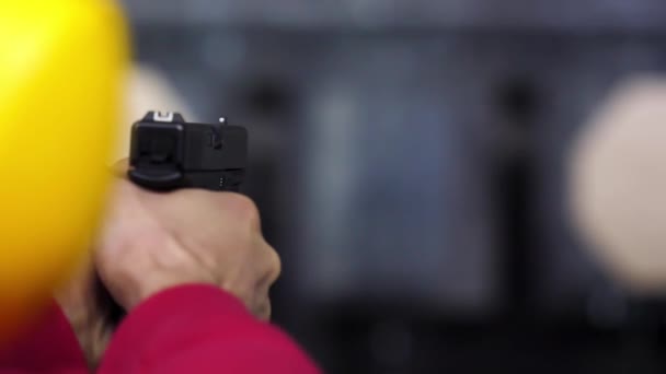 Vista trasera del hombre dispara un arma en el campo de tiro de cerca. Hombre dispara pistola de mano en el campo de tiro interior. De cerca. Primer plano de las manos masculinas con un arma, el hombre entrena para disparar visión trasera — Vídeo de stock