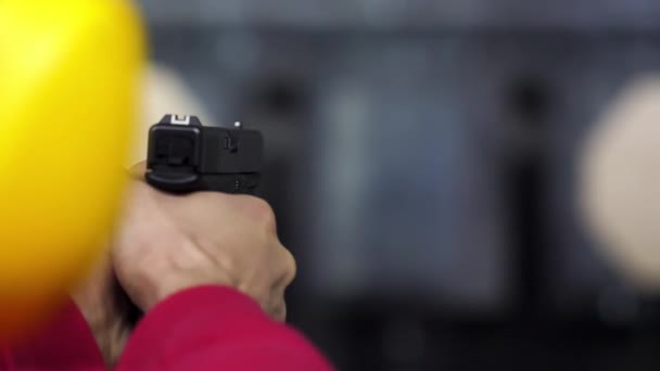 Vista trasera del hombre dispara un arma en el campo de tiro de cerca. Hombre dispara pistola de mano en el campo de tiro interior. De cerca. Primer plano de las manos masculinas con un arma, el hombre entrena para disparar visión trasera — Vídeo de stock