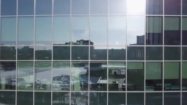 Blauwe glazen wand van wolkenkrabber met reflectie van de zon. Moderne architectuur met sun ray van juiste hoek. De reflectie van het zonlicht op glazen gebouw. Crosswalk foto boven de weg — Stockvideo