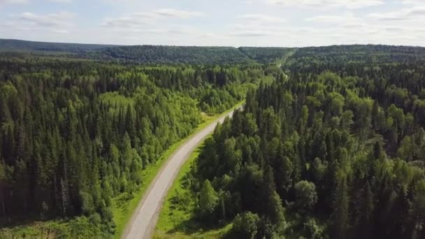 Vista aérea del coche blanco que conduce en la carretera del país en bosque. Vista aérea volando sobre viejo parcheado carretera forestal de dos carriles con el coche en movimiento árboles verdes de bosques densos que crecen a ambos lados. Coche conduciendo — Vídeos de Stock