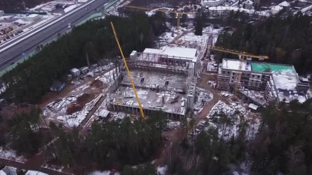 Luftaufnahme einer Großbaustelle. Ein Wohnhochhaus und ein Baukran. Bau von Hochhäusern im Winter. Luftbild. — Stockvideo