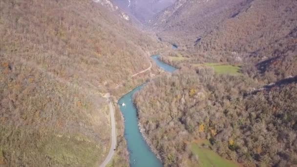 Горная река в ущелье между скалами и деревьями, воздушный вид на горный пейзаж. Клип. Вид с воздуха на реку, протекающую между лавовыми скалами и горой — стоковое видео