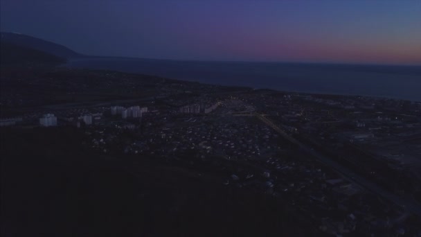 Panorama noturno da cidade de Sochi a partir de uma visão de olhos de pássaros. Clipe. Panorama de Sochi do ar. Casas, ruas, árvores, o céu noturno são visíveis. À distância você pode ver o mar. Sochi, Rússia — Vídeo de Stock