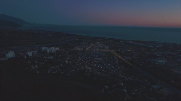 Panorama nocturno de la ciudad de Sochi desde una vista de pájaro. Clip. Panorama de Sochi desde el aire. Casas, calles, árboles, el cielo nocturno son visibles. En la distancia se puede ver el mar. Sochi, Rusia — Vídeo de stock