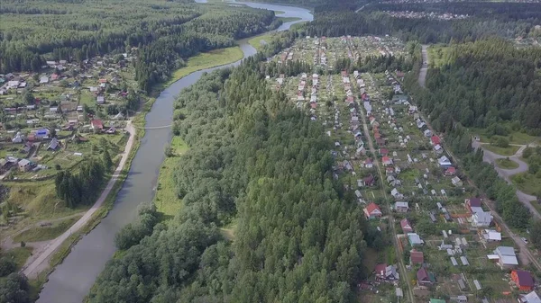 Letecký pohled na městečko nedaleko lesa. Klip. Letecký pohled na město v zalesněné oblasti s řekou — Stock fotografie