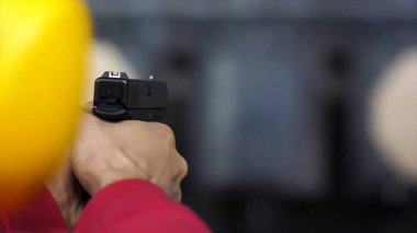 Arkadan adam sürgünler aralığı silah, bir tabanca yakından görünüşü. Adam kapalı atış poligonuna el silah patlar. Yakın çekim. Erkek elinde bir silahla adam trenler dikiz vurmaya yakın çekim