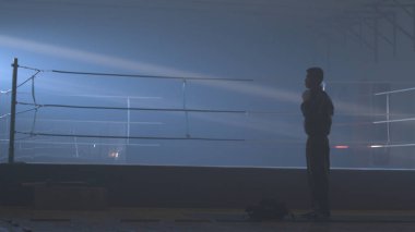 Grunge arka plan üzerinde arkadan görünüm genç boksör. Savaşçı adam siluet karanlık. MMA savaşçı siluet karanlık halkası üzerinde. Boksör mücadele önce sahnede duruyor. Boksör siluet duman karanlık stüdyoda. Arkadan görünüş