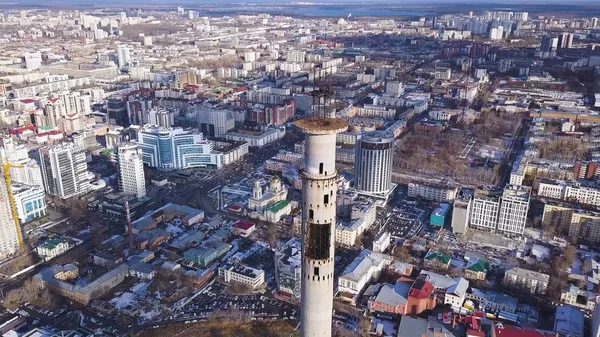 Close-up view of the TV tower from copter flying up at the background of the city in winter during the sunset.