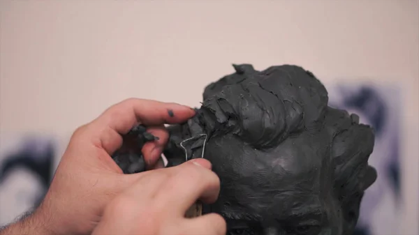 Uno scultore che lavora alla sua scultura in argilla nella sua bottega. Clip. L'uomo taglia uno stampo di argilla — Foto Stock