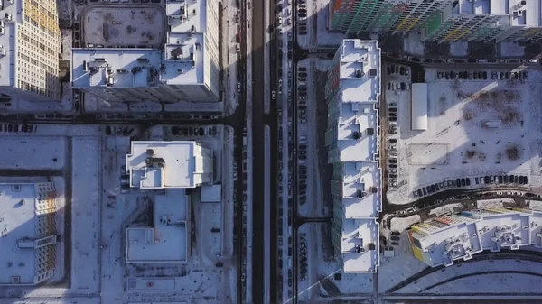 Aerial view snow-covered road with cars in winter. Clip. Aerial view on city in winter day. City panorama with straight road covered with snow from a bird eye view. Winter city streets from a bird eye — Stock Photo, Image