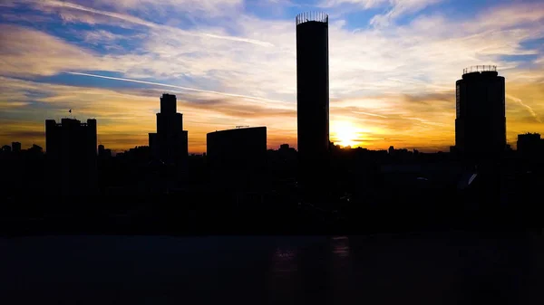 Luftaufnahme eines wunderschönen, farbenfrohen, dramatischen Sonnenuntergangs über der Silhouette der Stadt. Clip. Stadtsilhouetten bei Sonnenuntergang mit Wolkenkratzern im Hintergrund. Sonnenuntergang in der Stadt mit Geschäftszentren Hintergrund — Stockfoto