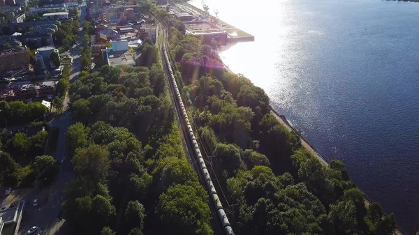 Treno merci con carbone su rotaie a due lati avvolgenti vicino al fiume in estate giornata di sole, Vista aerea dall'alto. Clip. Vista sulle corse treno merci sui binari vicino foresta. Carri ferroviari. Trasporti. — Foto Stock