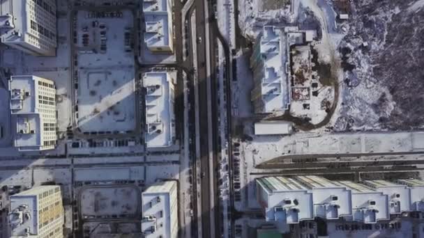 Vista aérea cubierta de nieve carretera con coches en invierno. Clip. Vista aérea de la ciudad en el día de invierno. Panorama de la ciudad con camino recto cubierto de nieve desde una vista de pájaro. Las calles invernales de la ciudad del ojo de pájaro — Vídeo de stock