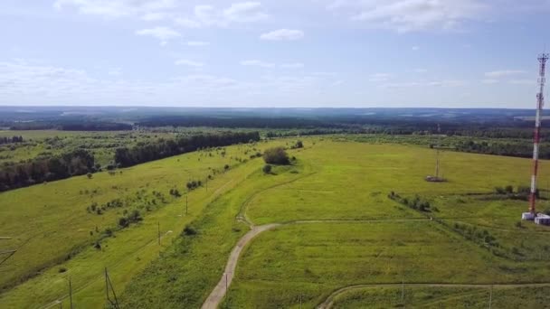 Bela paisagem com colinas baixas e vales vistos de cima, com neblina na distância. Clipe. Vista aérea do campo verde com floresta na hora de verão — Vídeo de Stock