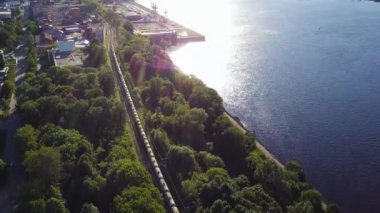 İki taraflı Demiryolları nehir kenarında yaz güneşli gün, hava üstten görünüm sarma üzerinde kömür ile yük treni. Küçük. Yük treni sürmek forest yakınındaki pistlerde görüntüleyin. Demiryolu vagonlar. Ulaşım