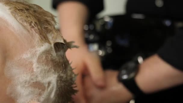 Cabeleireiro lavando cabelo para seu cliente bonito. Clipe. Barbeiro no trabalho. Homem na barbearia — Vídeo de Stock