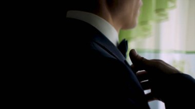 Adam bir ceket koyarak. Şık adam giyer kelebek ceketle düzeltiyor. Küçük. Adam onun ceketi giymek