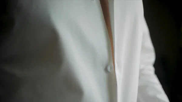 Um homem de negócios de perto veste uma camisa branca. Clipe. Close up de homem vestir-se e ajustar camisa branca com abotoaduras. O homem com a camisa branca nos botões de punho do vestido da janela . — Fotografia de Stock