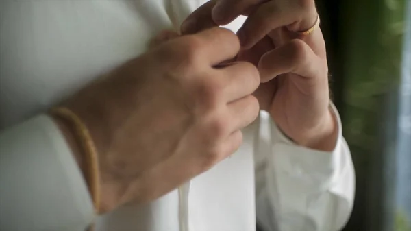 Close up van zakenman draagt een wit overhemd. Clip. Close-up van man verkleden en wit overhemd met Manchetknopen aan te passen. De man in het witte shirt in de venster jurk Manchetknopen. — Stockfoto