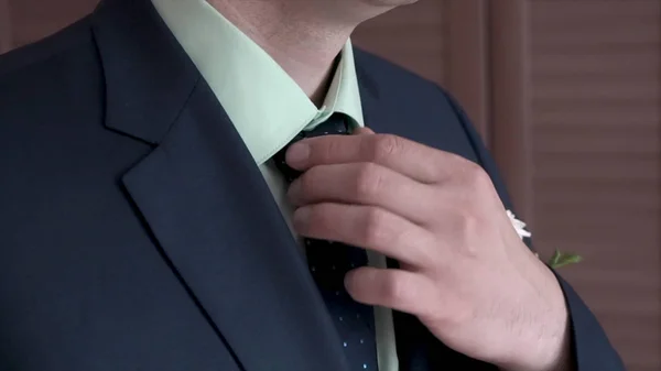 Portrait of businessman adjusting his necktie standing in office. Clip. Man in a black suit and white shirt straightens his tie with his hands, a close-up without a face — Stock Photo, Image