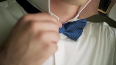 Smokinini düzleştirme bir adam yakın çekim bir kadeh. Küçük. Smokin düzleştirme onun papyon, iki el, hiç ceket bir adam close-up. Adam kravatını düzeltiyor