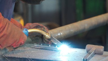 İşçi kaynak metal koruyucu maske ile. Bir adam bir metal kaynak makinası ile kaynak. Kaynakçı fabrikada çalışan ve bir metal konstrüksiyon kaynak. Fabrikada çalışan kaynakçılar metal yapılmış