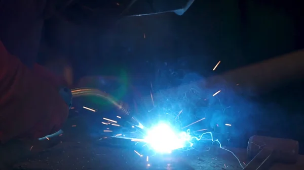 Trabalhador com máscara protetora soldagem de metal. Um homem solda um metal com uma máquina de solda. Soldador está trabalhando na fábrica e soldando uma construção de metal. Soldadores que trabalham na fábrica feita de metal — Fotografia de Stock