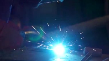 İşçi kaynak metal koruyucu maske ile. Bir adam bir metal kaynak makinası ile kaynak. Kaynakçı fabrikada çalışan ve bir metal konstrüksiyon kaynak. Fabrikada çalışan kaynakçılar metal yapılmış