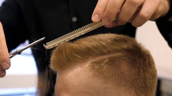 Primo piano di mens taglio di capelli forbici in un salone di bellezza. Master taglia i capelli e la barba degli uomini nel barbiere, parrucchiere fa acconciatura per un giovane uomo. Primo piano di Man al Salone da parrucchiere — Foto Stock