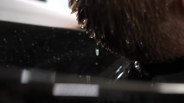 Close-up van de mens om haar gewassen in een kapsalon, waterdruppels die vallen in slow motion. Kapper wassen klanten haar in de kapsalon. Close-up van vallende druppels water terwijl Kapper wast — Stockvideo