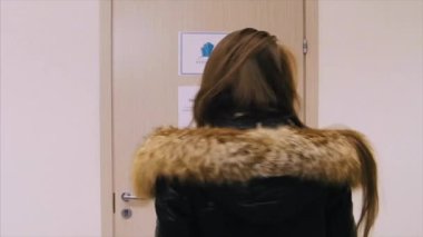 Kış ceket ayakta karşısında üzgün ve kızgın kapıyı kız görünümünü arka. kız ofis kapı duruyor ve neden kapalı olduğunu anlamıyor. Düşünme kadın arkadan görünüm