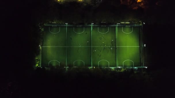 サッカー場の周りを実行しているサッカー選手。夜のトレーニング。試合の準備。高度からドローンと空中ショットは。フットボールまたはサッカー フィールドの夜空中。黒と白のミニ — ストック動画