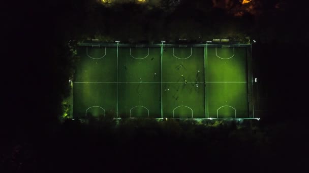 Football players running around the football field. Night workout. Preparation for the match. Aerial shot with a drone from a altitude. Footbal or soccer field night aerial . black and white mini — Stock Video