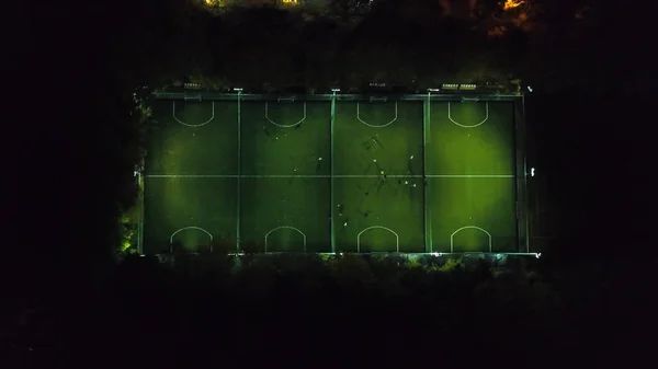 Les joueurs de football courent autour du terrain de football. Entraînement nocturne. Préparation pour le match. Prise de vue aérienne avec un drone d'altitude. Footbal ou terrain de football aérien de nuit. mini noir et blanc — Photo