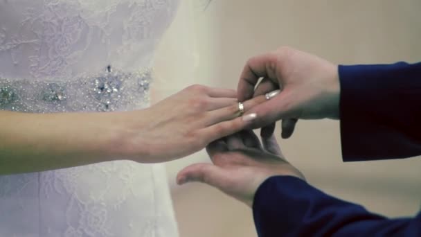 Colocar anel na mão. Fechar-se de um noivo que põe uma aliança de casamento dourada no dedo de noivas — Vídeo de Stock