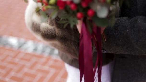 Gros plan d'une mariée tenant un bouquet de mariage avec des roses rouges. Mariée tenant des fleurs 