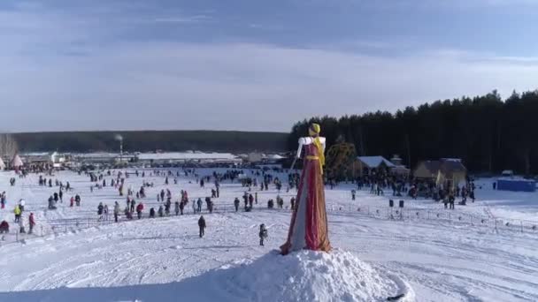 Muitas pessoas olham a queimadura do manequim durante a celebração de férias tradicionais russas Maslenitsa à tarde de inverno. Filmagem. Vista aérea — Vídeo de Stock