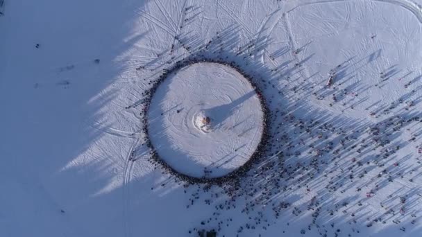 Círculo de pessoas que olham a queimadura do manequim durante a celebração de férias tradicionais russas Maslenitsa. Filmagem. Vista aérea — Vídeo de Stock