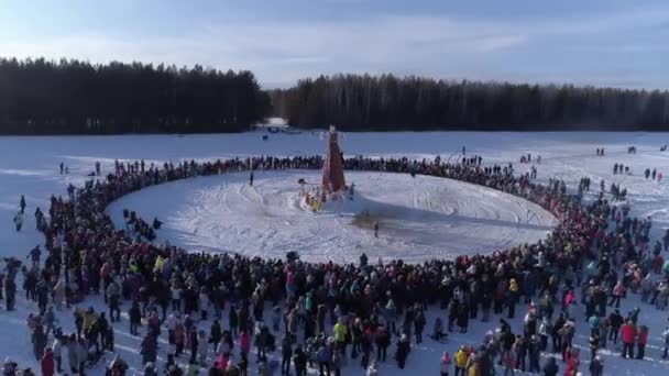 Muchas personas miran la quema del maniquí durante la celebración de la fiesta tradicional rusa Maslenitsa en la tarde de invierno. Filmación. Vista aérea — Vídeo de stock