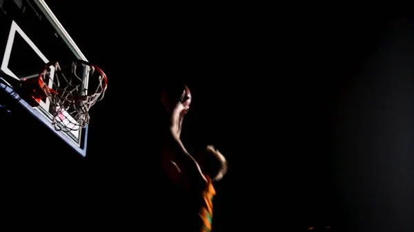 Primer plano de una pelota de baloncesto pasando por la red para un gol de campo. Un primer plano de un jugador de baloncesto corriendo y hundiendo la pelota. Primer plano del jugador de baloncesto haciendo slam dunk en el juego de baloncesto — Foto de Stock