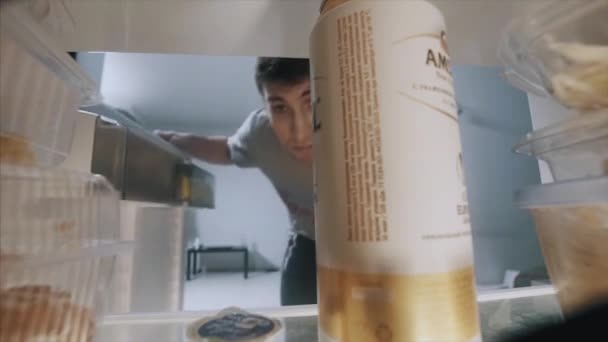 Um homem a tirar cerveja do frigorífico. O homem tira uma cerveja do frigorífico. Vista da geladeira — Vídeo de Stock