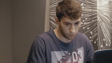 Gece geç saatlerde çalışma, bir dizüstü bilgisayar kullanarak, masada oturan genç adam, o Gürültücü komşular tarafından bozulmuştur