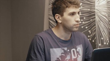 Gece geç saatlerde çalışma, bir dizüstü bilgisayar kullanarak, masada oturan genç adam, o Gürültücü komşular tarafından bozulmuştur