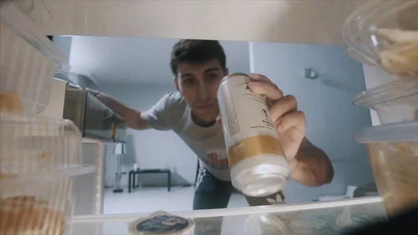 Un uomo che prende birra dal frigo. Un uomo prende una birra dal frigo. Vista dal frigorifero — Foto Stock