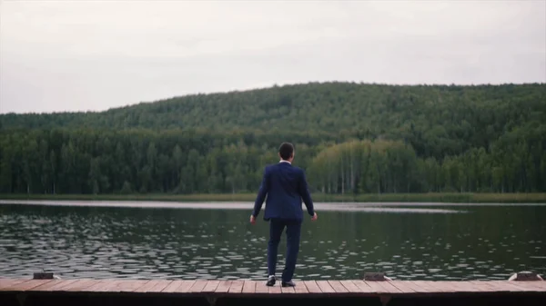 Bakifrån av affärsmannen tittar på pittoreska natur landskap. Klipp. Bakifrån av affärsman på sjön — Stockfoto