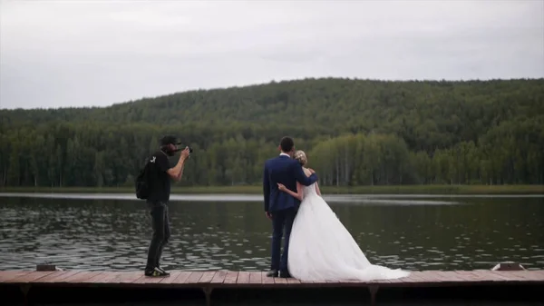 Photographer takes photos of the bride and groom. Clip. Couple. The bride in a white dress and groom on the lake. Rear view on ride and groom on the lake — Stock Photo, Image