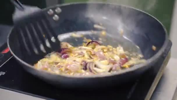 Cebolas de cozinha em uma panela de ato de fritar. Clipe. Fritando cebolas em uma panela de ferro fundido — Vídeo de Stock